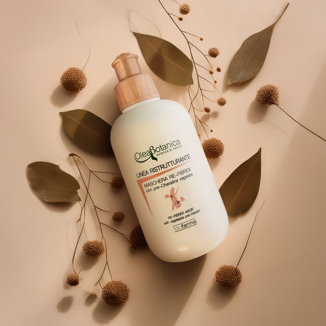 flacone bianco maschera rigenerante fidufarma su sfondo rosa neutro accerchiato da foglie e soffioni