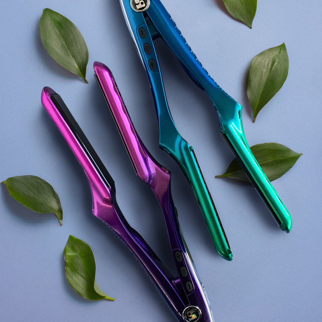 Due piastre di due colori diversi. Una piastra rosa e una sfumata dal blu al verde. Poggia su uno sfondo azzurro. Di fianco delle foglie verdi.