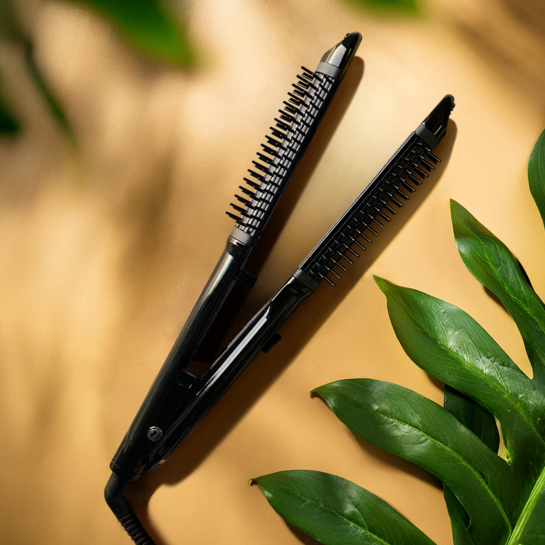 Piastra con spazzola nelle piastre nera, che poggia su uno sfondo neutro ocra e con delle foglie verdi