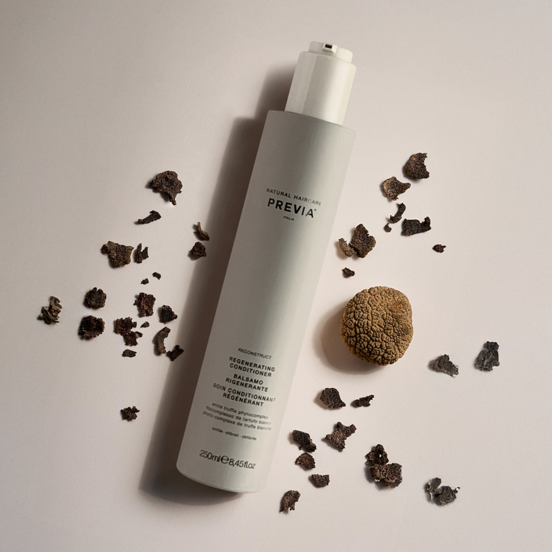 flacone balsamo rigenerante su sfondo neutro accerchiato da pezzi di noce