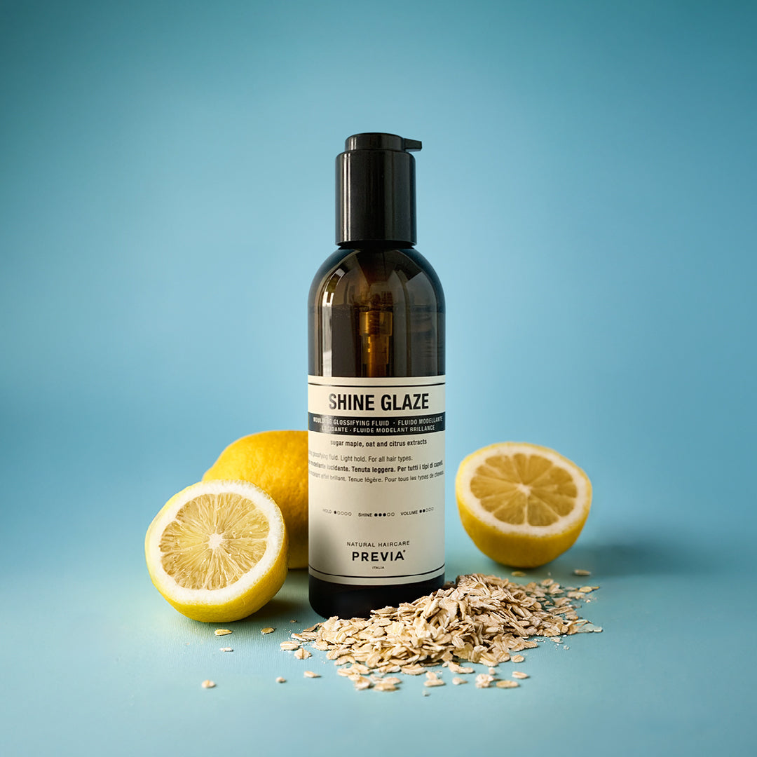 flacone fluido modellante lucidante su sfondo azzurro accerchiato da limini e cereali