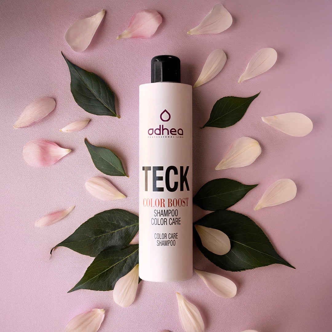 sfondo rosa con in mezzo un flacone bianco circondato da foglie verdi e petali bianchi