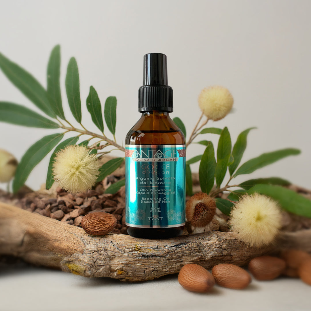 Prodotto Tmt Gocce di Olio che poggia su un tronco, attorno delle mandorle e dei soffioni