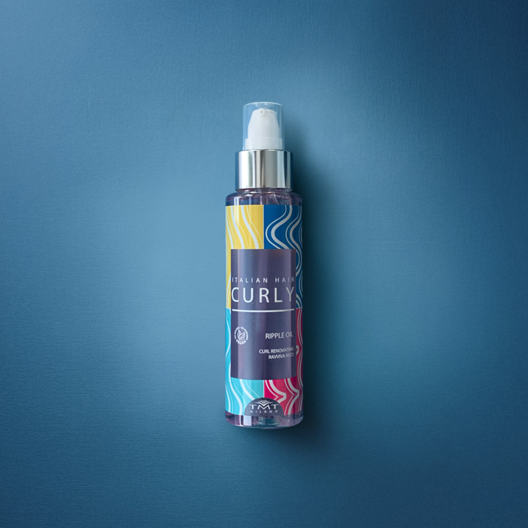 Flacone Curly Ripple Oil di Tmt molto colorato che poggia su sfondo in tinta unita fucsia
