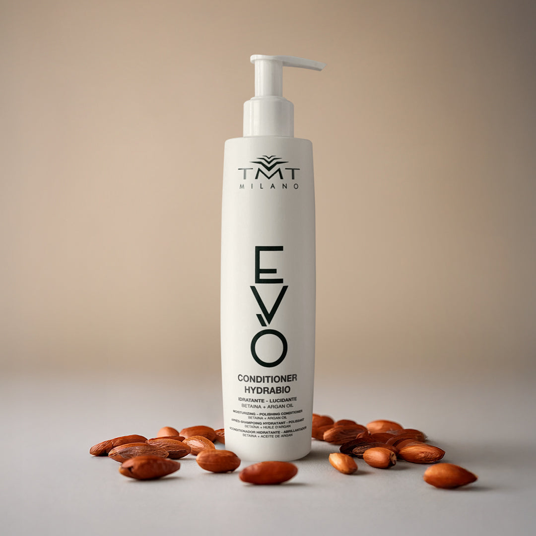 Flacone Evo condizionante lavaggi frequenti su sfondo neutro rosa con attorno mandorle