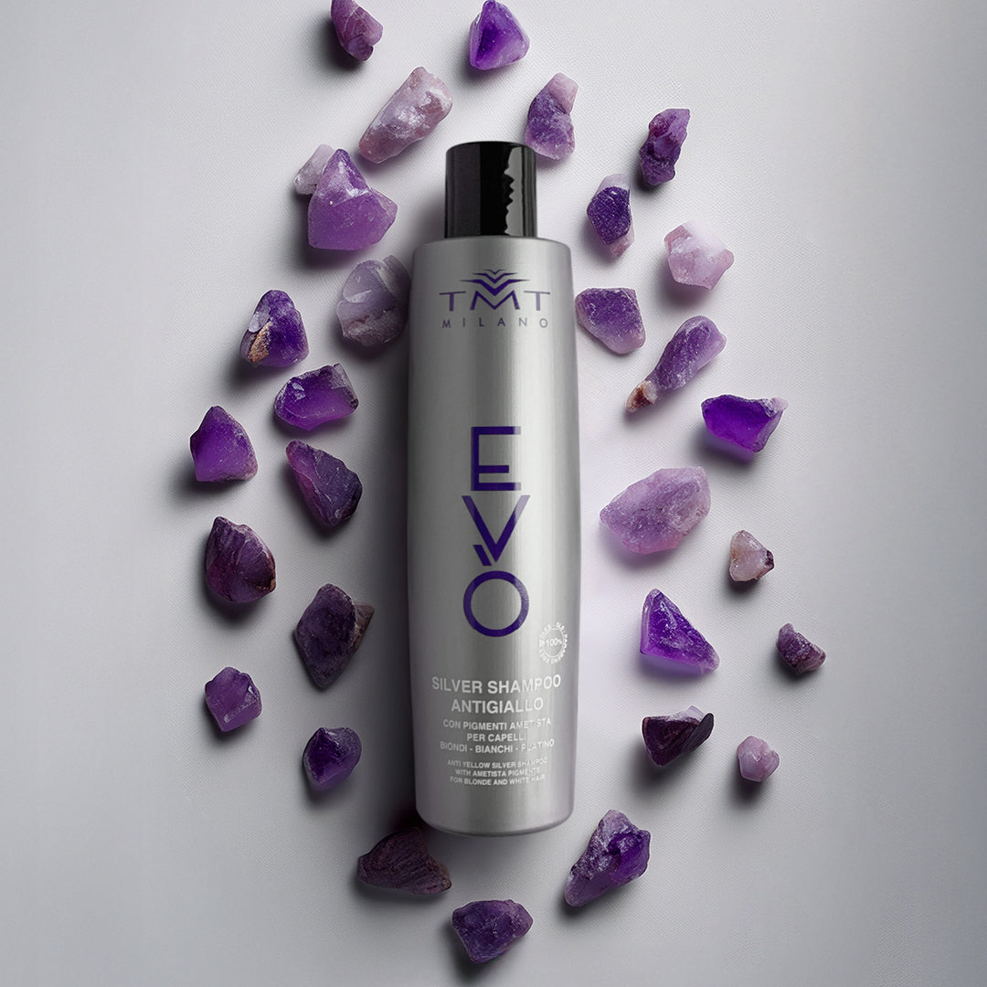 Flacone Evo Shampoo Antigiallo su sfondo neutro grigio con attorno pietre viola