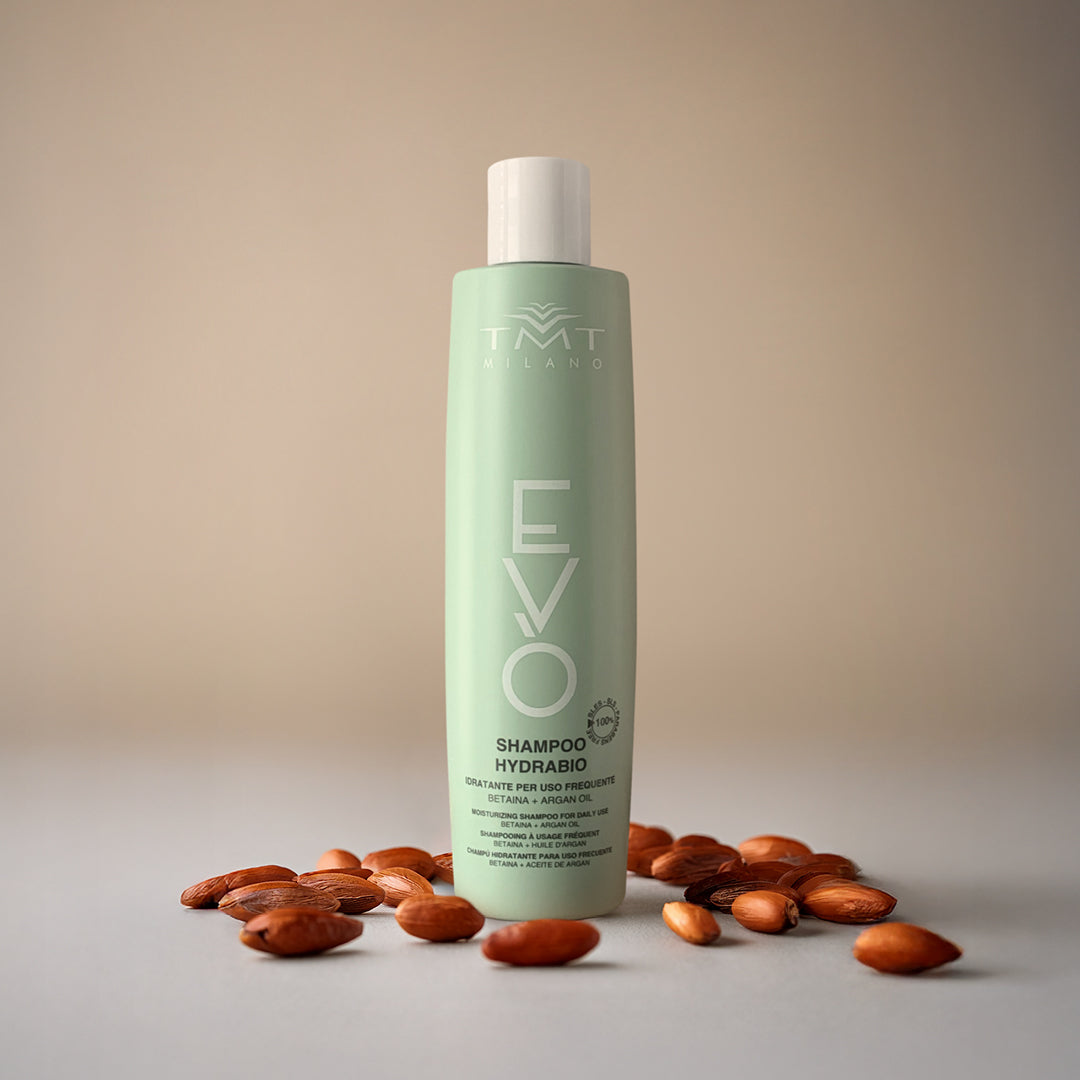 Flacone Evo shampoo lavaggi frequenti su sfondo neutro rosa con attorno mandorle