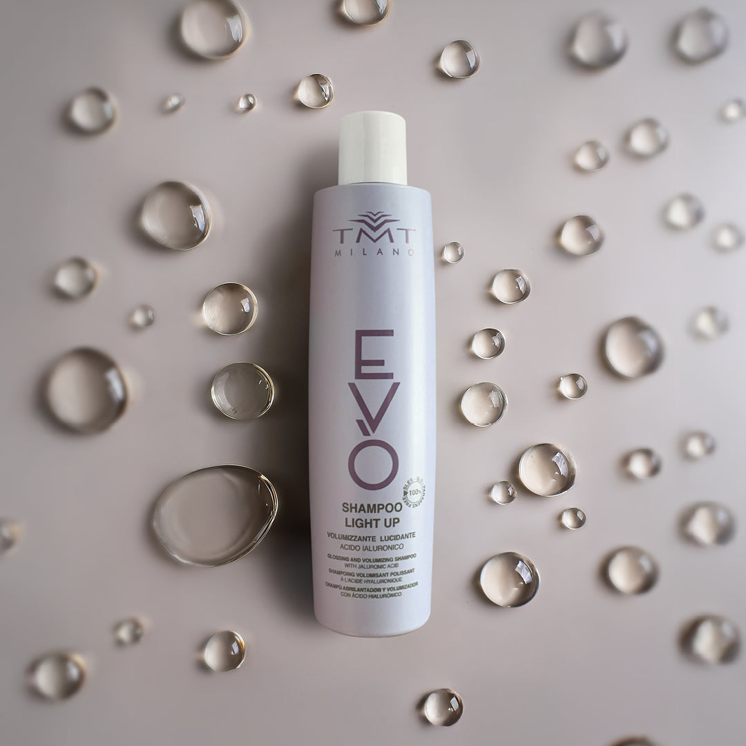 Flacone Evo Shampoo volumizzante su sfondo neutro grigio con una serie di bolle d'acqua