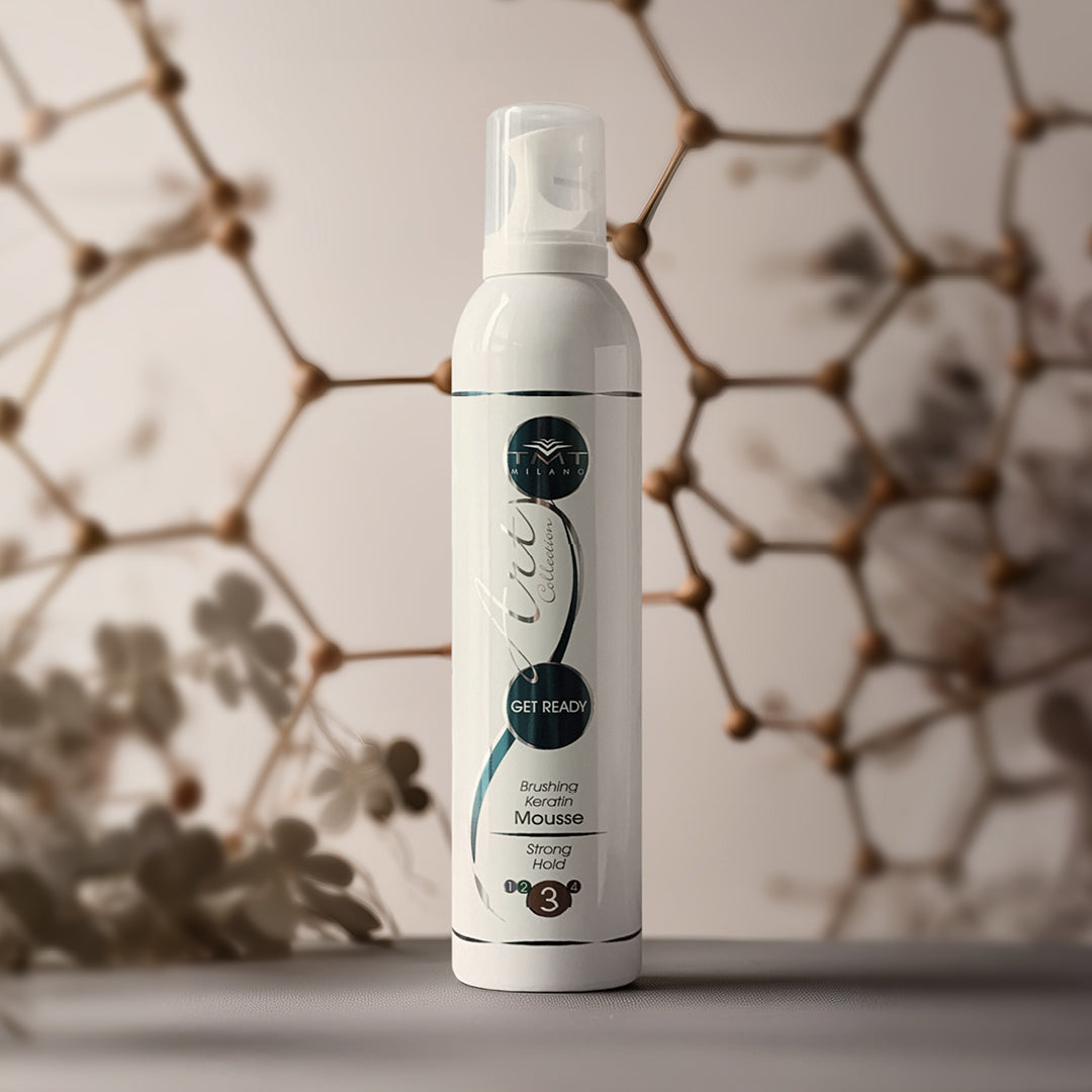 flacone biancodi mousse di get ready tmt che poggia su un piano grigiio e dietro una struttura di palline in legno
