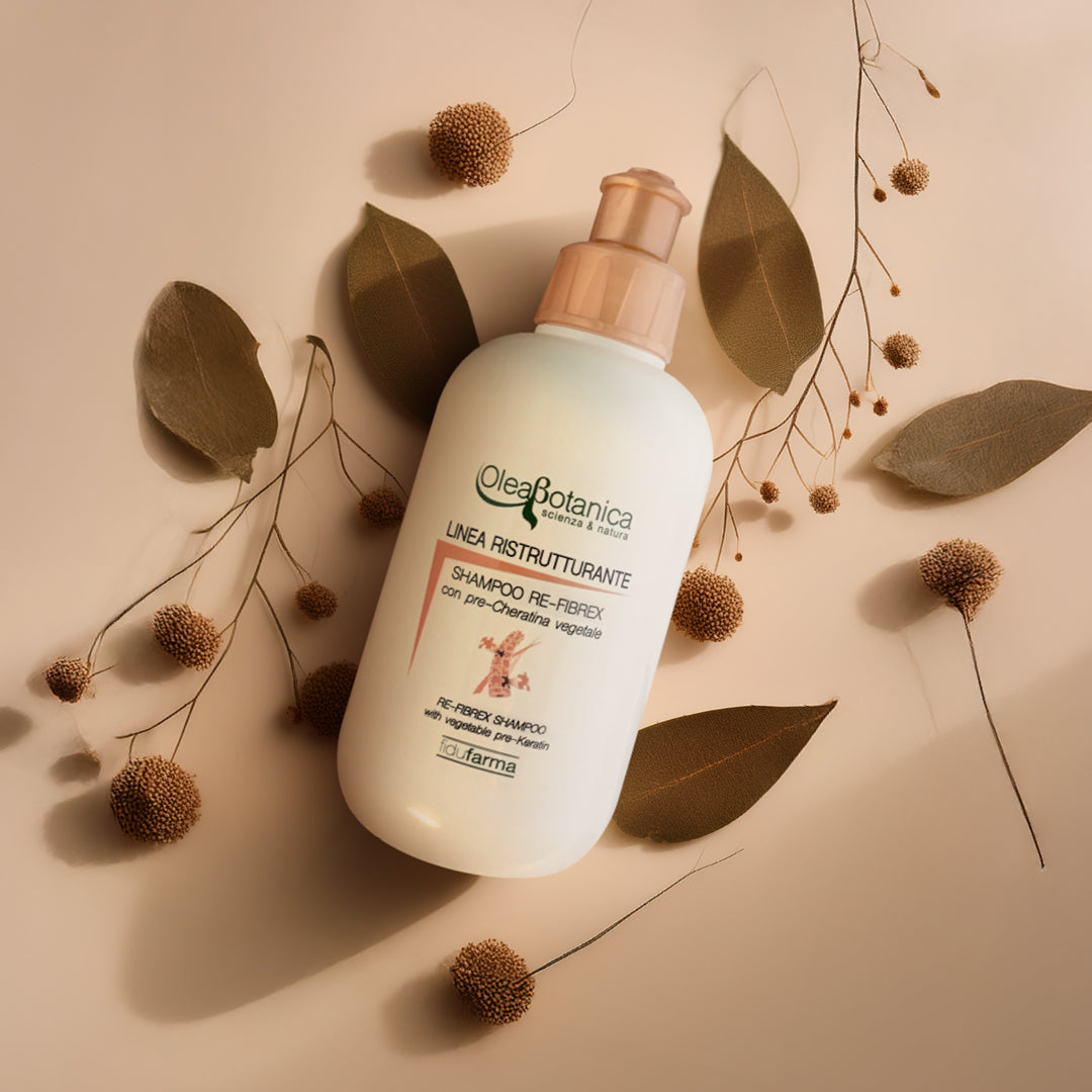 flacone bianco shampoo ristrutturante fidufarma su sfondo neutro con foglie e soffioni