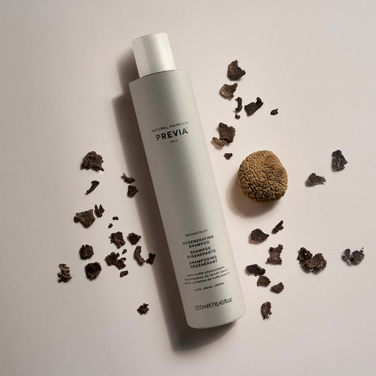 flacone shampoo rigenerante su sfondo neutro accerchiato da pezzi di noce