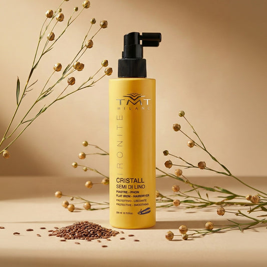 immagine Spray termoprotettivo Ironite ambientato su sfondo neutro caldo, circondato da Semi di Lino e rami verdi con boccioli di fiori 