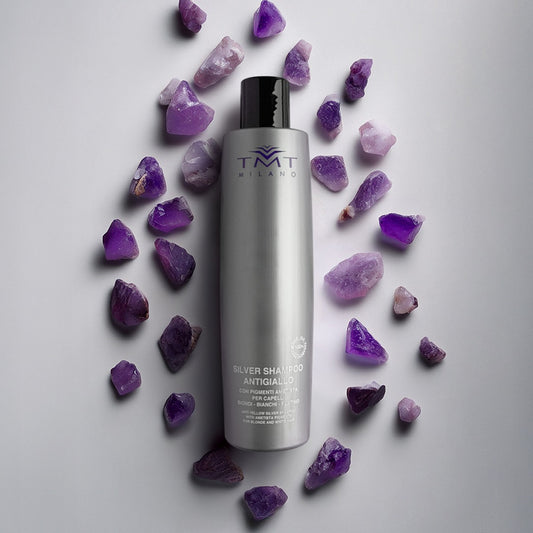 Flacone Evo Shampoo Antigiallo su sfondo neutro grigio con attorno pietre viola