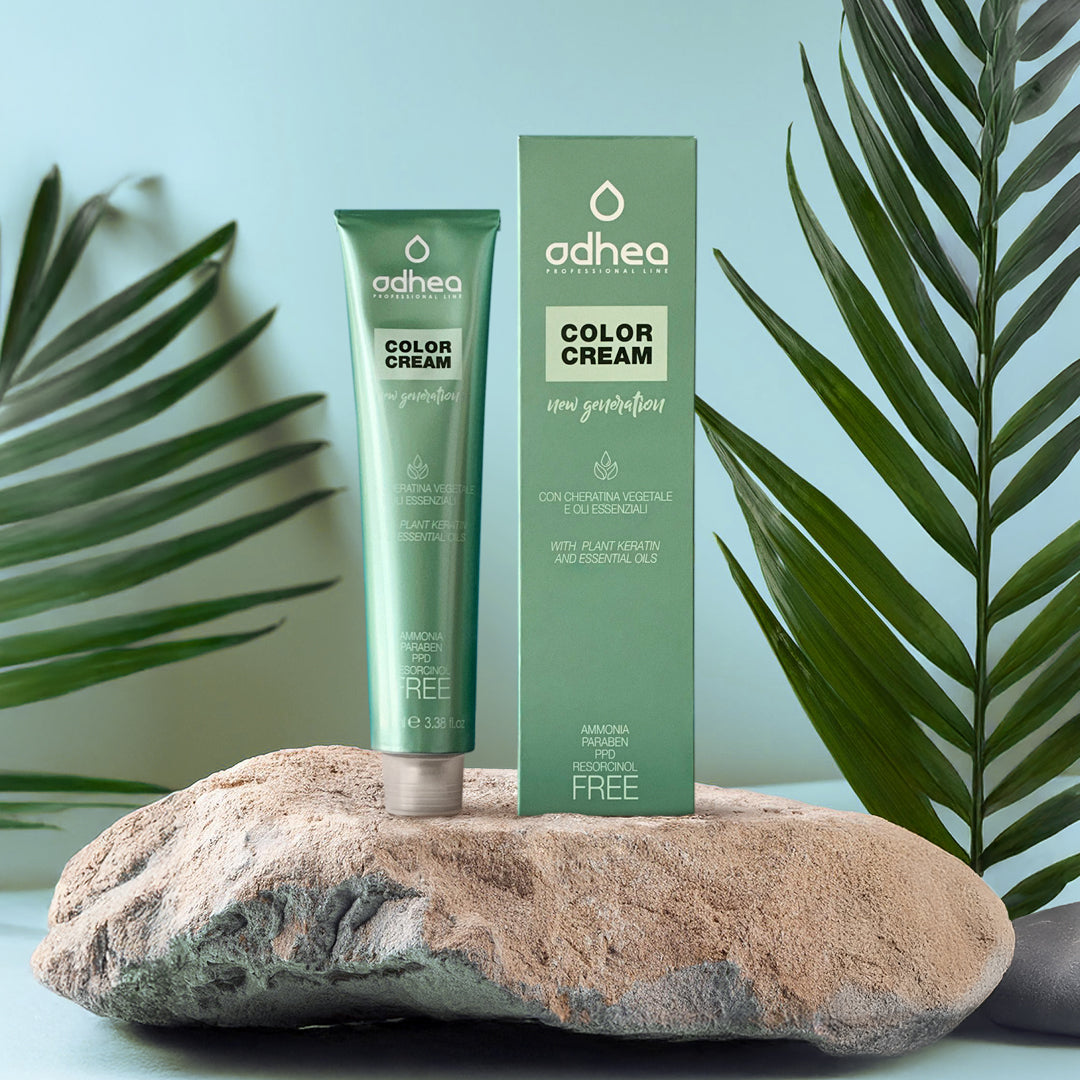 tubo di alluminio verde e a fianco atuccio verde, entrambi appoggiati su un sasso bianco, e ai lati dell'immagine due rami di foglie