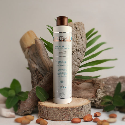 Prodotto Tmt Shampoo Ricostruente che poggia su un tronco e anche dietro ce ne sono due. attorno delle mandorle