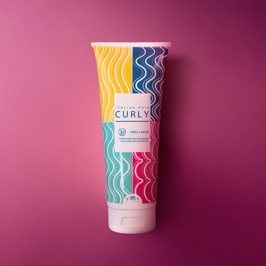 Flacone Curly Freely Mask di Tmt molto colorato che poggia su sfondo in tinta unita fucsia