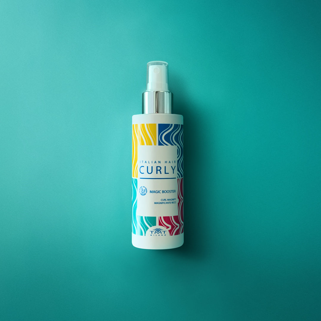 Flacone Curly Magic Booster di Tmt molto colorato che poggia su sfondo in tinta unita fucsia