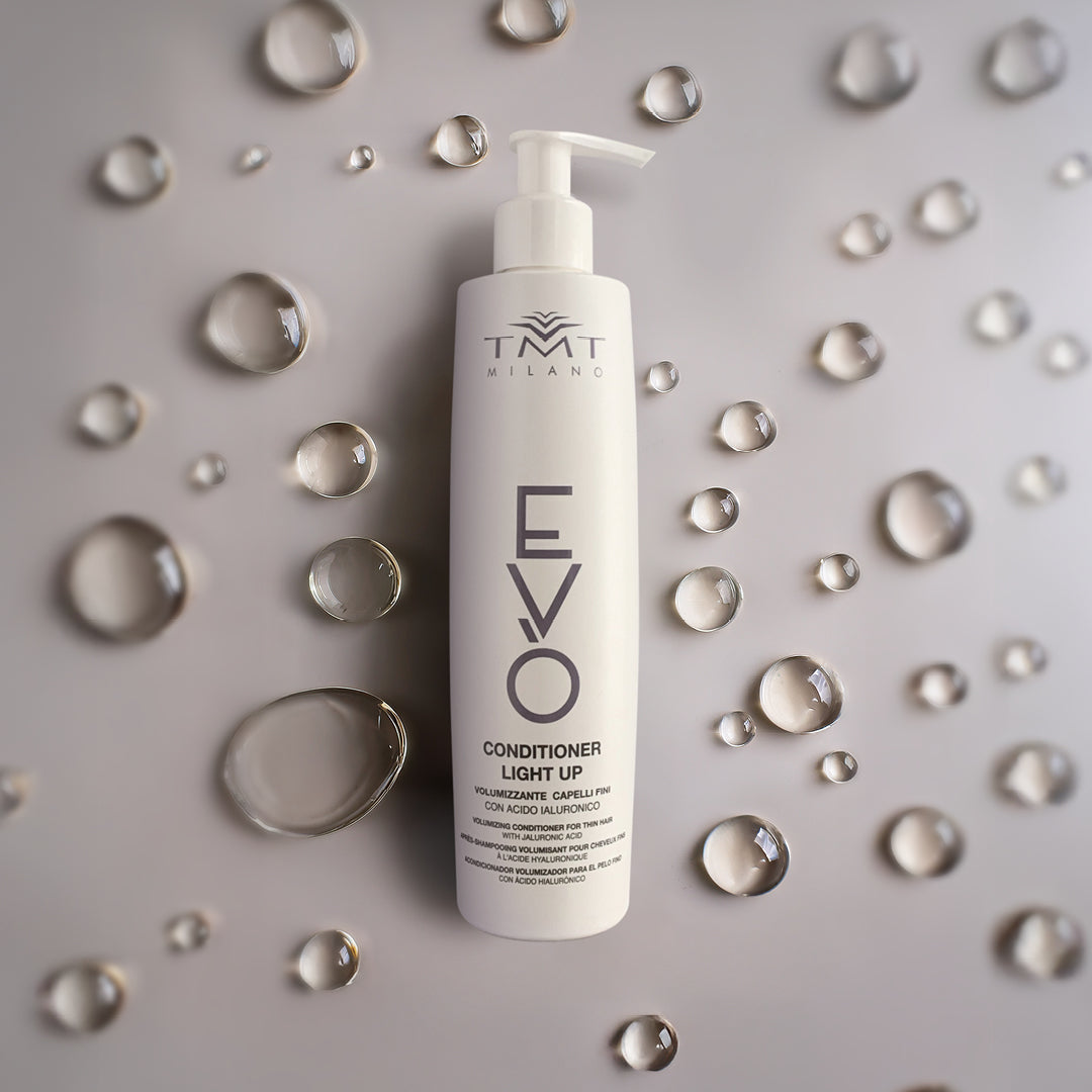 Flacone Evo Condizionante volumizzante su sfondo neutro grigio con una serie di bolle d'acqua